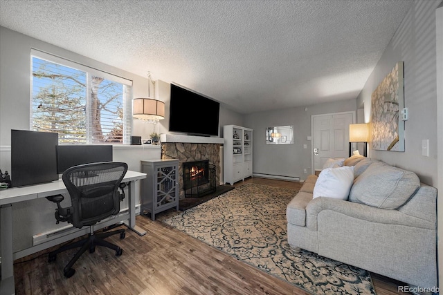 home office with a fireplace, a textured ceiling, a baseboard radiator, and hardwood / wood-style flooring