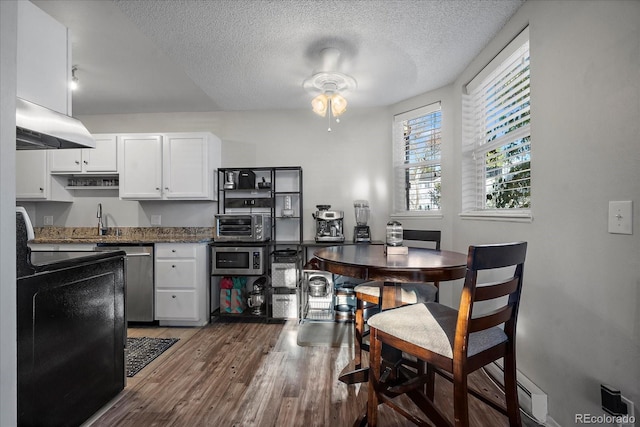 kitchen with dark stone countertops, a textured ceiling, appliances with stainless steel finishes, dark hardwood / wood-style flooring, and white cabinetry