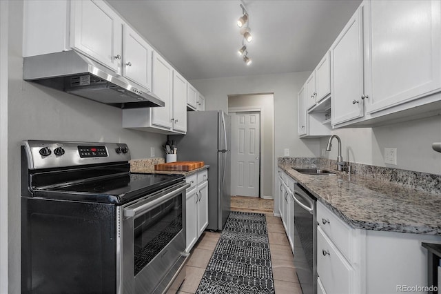 kitchen with stainless steel appliances, sink, stone counters, white cabinets, and light tile patterned flooring