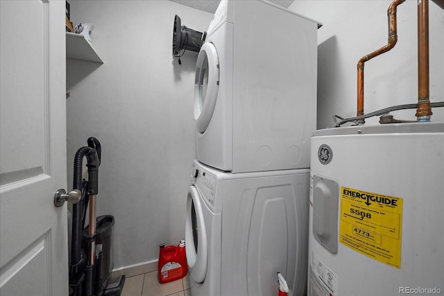 washroom with a textured ceiling, electric water heater, stacked washer / drying machine, and light tile patterned flooring