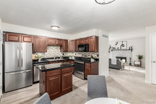 4784 S Tabor St, Morrison, CO 80465 - kitchen with appliances with stainless steel finishes, tasteful backsplash, a kitchen island, a stone fireplace, and open floor plan