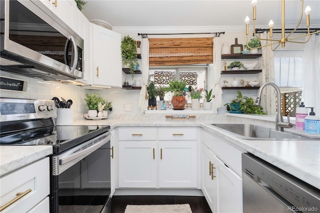 9620 W Chatfield Ave Unit D, Littleton, CO 80128 - kitchen with appliances with stainless steel finishes, open shelves, a chandelier, crown molding, and decorative backsplash