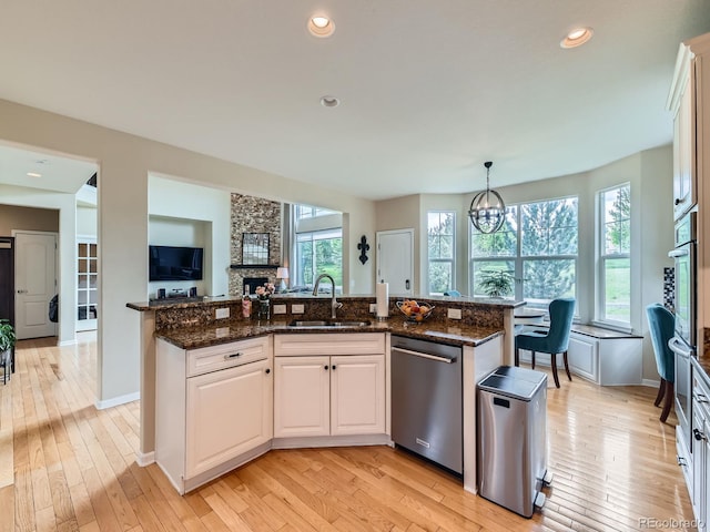 2896 Gemini Loop, Broomfield, CO 80023 - kitchen with stainless steel appliances, a sink, a stone fireplace, white cabinetry, and a chandelier