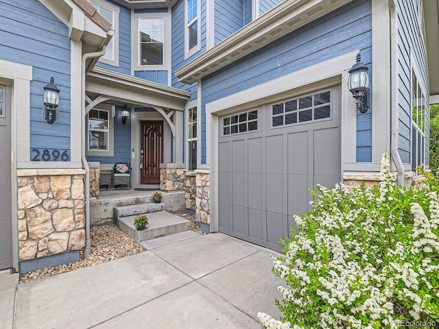 2896 Gemini Loop, Broomfield, CO 80023 - property entrance featuring an attached garage, driveway, stone siding, board and batten siding, and a porch