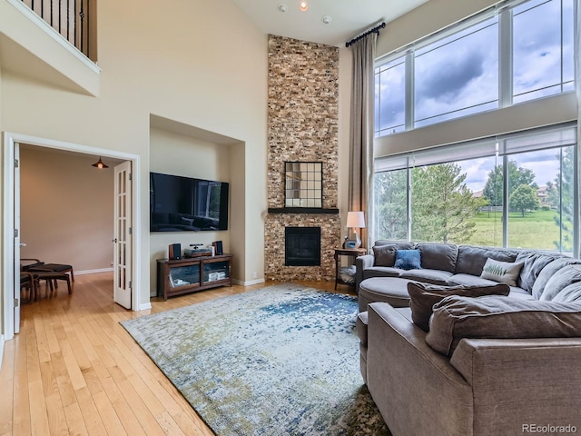 2896 Gemini Loop, Broomfield, CO 80023 - living room featuring a high ceiling, a stone fireplace, hardwood / wood-style flooring, baseboards, and recessed lighting