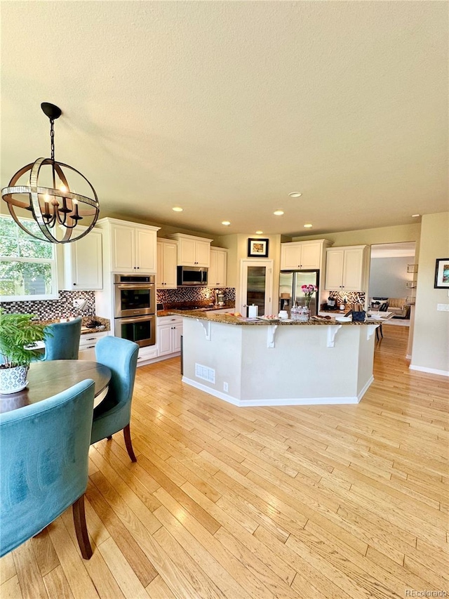 2896 Gemini Loop, Broomfield, CO 80023 - kitchen featuring stainless steel appliances, a chandelier, backsplash, a breakfast bar area, and recessed lighting