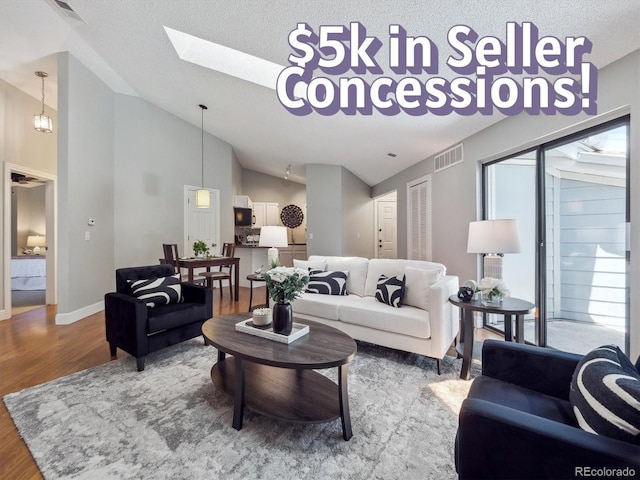5690 W 80th Pl Unit 101, Arvada, CO 80003 - living area with wood finished floors, lofted ceiling, baseboards, a textured ceiling, and a skylight