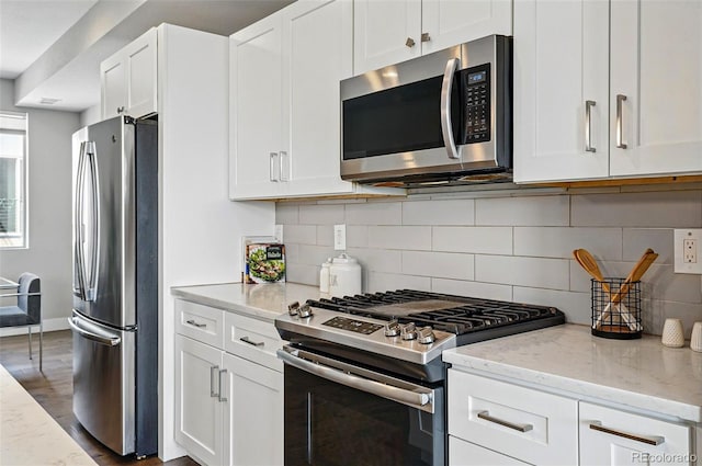 kitchen featuring white cabinetry, light stone countertops, appliances with stainless steel finishes, and tasteful backsplash