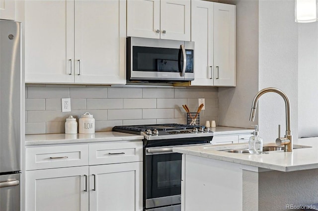 kitchen featuring a sink, decorative backsplash, appliances with stainless steel finishes, and white cabinets