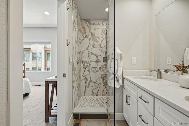 ensuite bathroom with a sink, a marble finish shower, ensuite bathroom, and recessed lighting