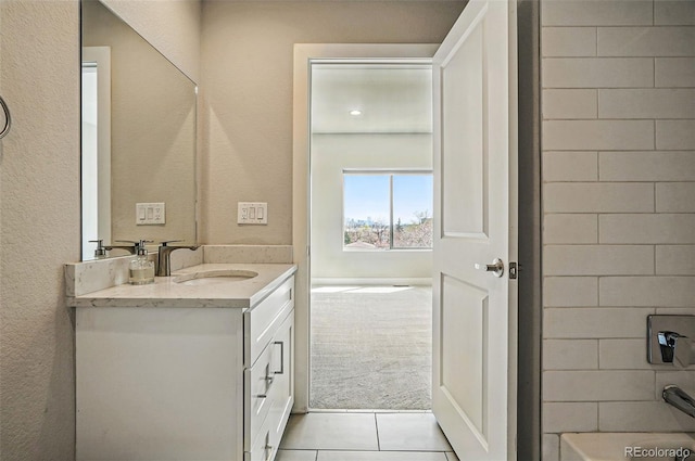 bathroom with vanity, a textured wall, tile patterned floors, and a bath
