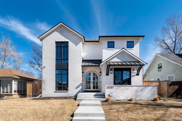 modern farmhouse style home featuring metal roof, a standing seam roof, fence, french doors, and brick siding