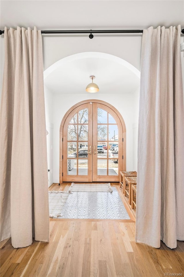 entrance foyer featuring arched walkways, french doors, and wood finished floors