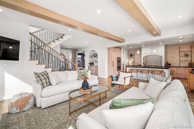 living room featuring recessed lighting, beamed ceiling, light wood-style flooring, and stairs