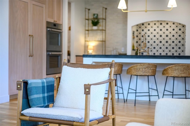 kitchen with light wood-type flooring, double oven, and a kitchen breakfast bar