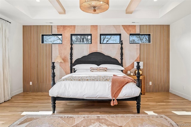 bedroom with visible vents, baseboards, beamed ceiling, and wood finished floors