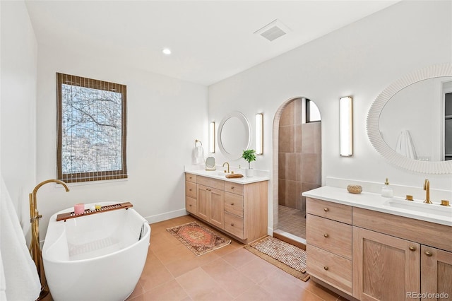 full bath with walk in shower, two vanities, a sink, and tile patterned flooring