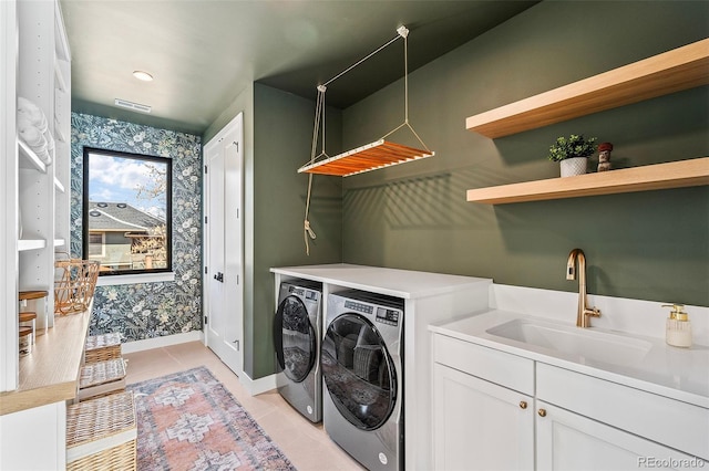 clothes washing area featuring baseboards, visible vents, washer and dryer, a sink, and light tile patterned flooring