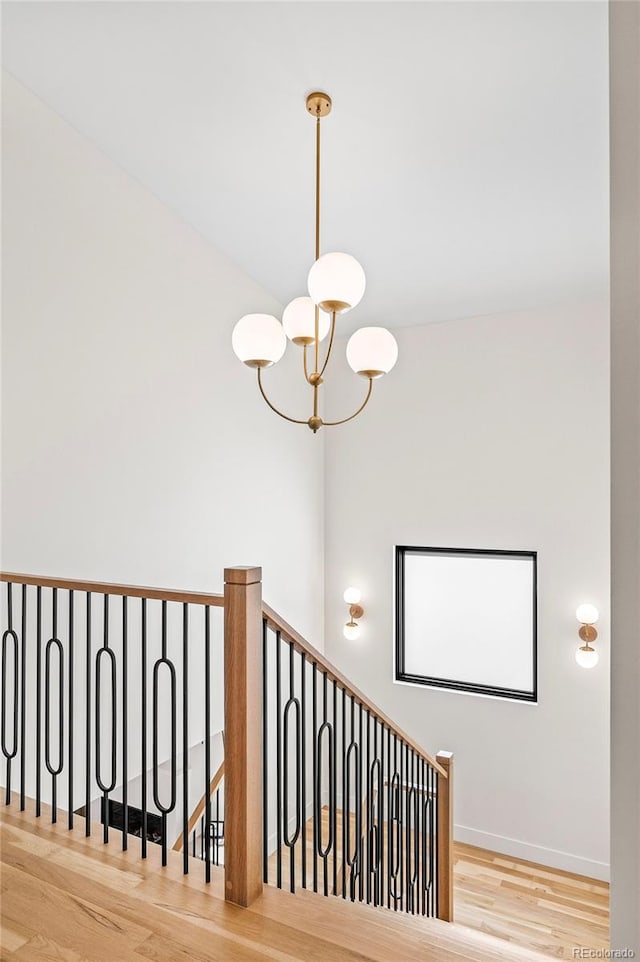 staircase with baseboards, wood finished floors, and a notable chandelier