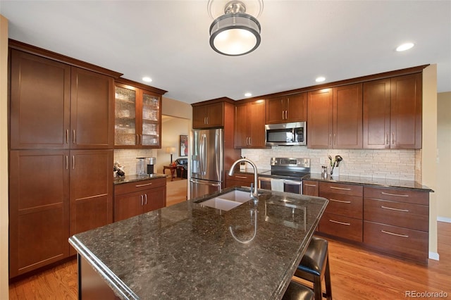 8040 W 78th Cir, Arvada, CO 80005 - kitchen featuring stainless steel appliances, a sink, backsplash, light wood-style flooring, and glass insert cabinets