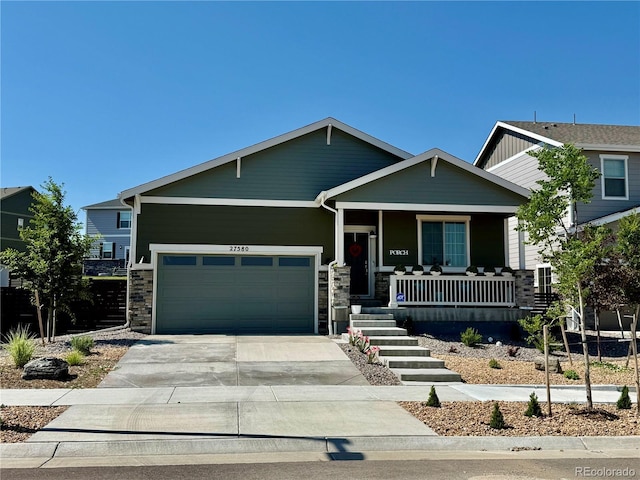 27580 E Cedar Pl, Aurora, CO 80018 - craftsman-style house with covered porch, an attached garage, stone siding, and driveway