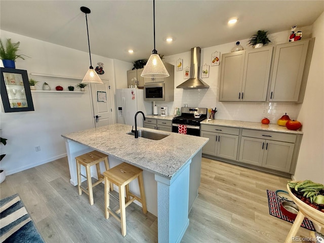 27580 E Cedar Pl, Aurora, CO 80018 - kitchen with wall chimney range hood, stainless steel gas range oven, white fridge with ice dispenser, built in microwave, and a kitchen island with sink