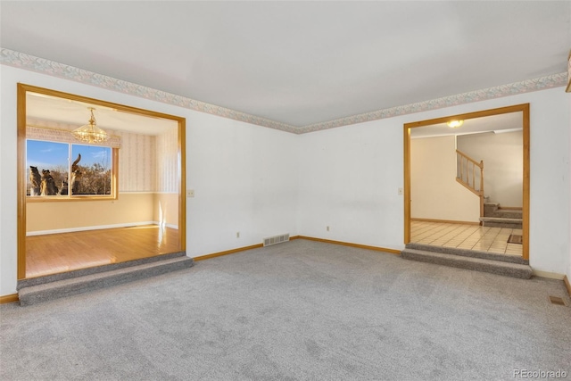 carpeted empty room with an inviting chandelier