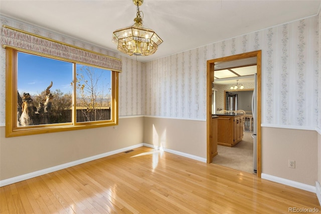 unfurnished room with light wood-type flooring and a chandelier