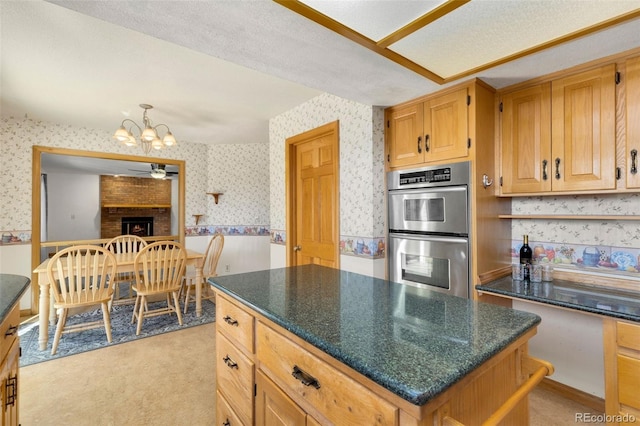 kitchen with a center island, stainless steel double oven, a brick fireplace, a textured ceiling, and light carpet