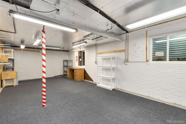 basement featuring dark carpet and brick wall