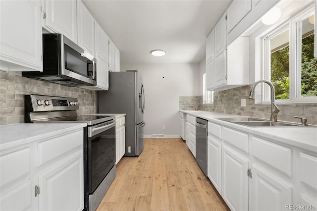 1304 S Lemay Ave, Fort Collins, CO 80524 - kitchen featuring stainless steel appliances, white cabinetry, backsplash, and light wood-style flooring