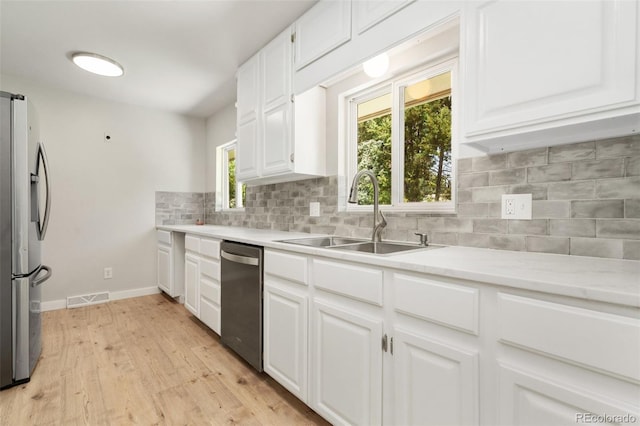 1304 S Lemay Ave, Fort Collins, CO 80524 - kitchen featuring stainless steel appliances, light wood finished floors, light countertops, tasteful backsplash, and white cabinets