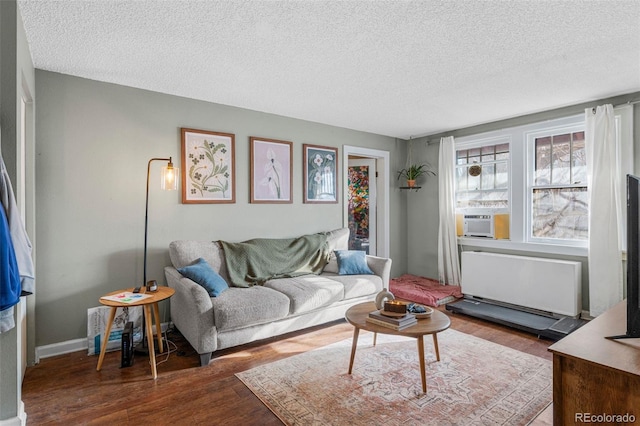 living area featuring radiator, baseboards, cooling unit, wood finished floors, and a textured ceiling