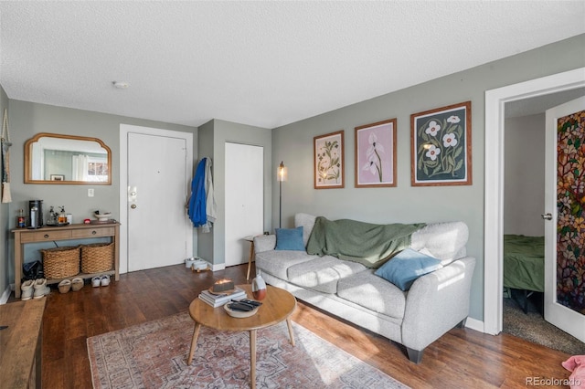 living room featuring a textured ceiling, baseboards, and wood finished floors