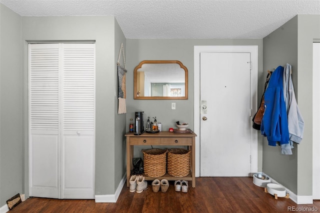 foyer entrance with wood finished floors, baseboards, and a textured ceiling