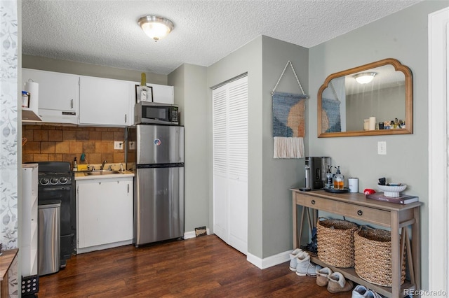 kitchen with dark wood-style floors, a sink, stainless steel appliances, white cabinets, and under cabinet range hood