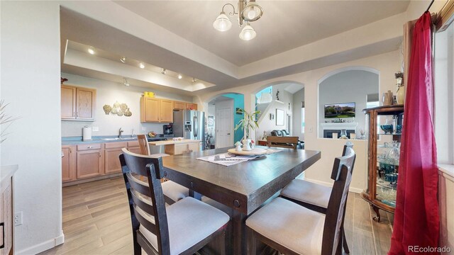 10449 Paris St Unit 207, Commerce City, CO 80640 - dining area with a raised ceiling, light wood finished floors, arched walkways, and a chandelier