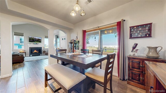 10449 Paris St Unit 207, Commerce City, CO 80640 - dining area featuring arched walkways, healthy amount of natural light, dark wood-style flooring, and a lit fireplace
