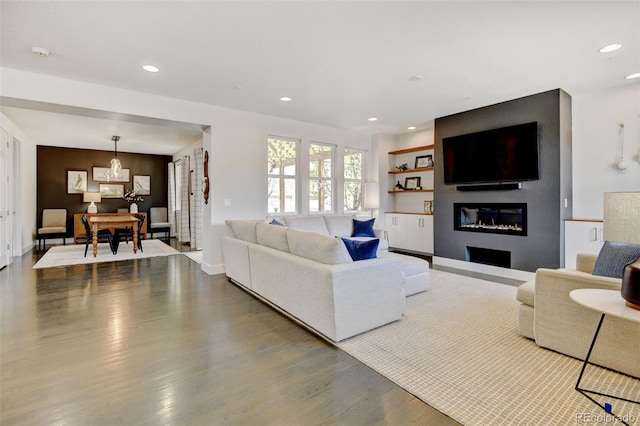 living room with recessed lighting, baseboards, a glass covered fireplace, and wood finished floors