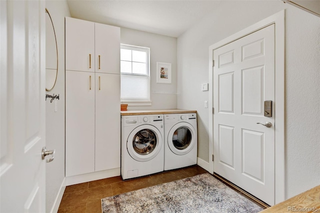 laundry area with dark tile patterned flooring, separate washer and dryer, and cabinet space