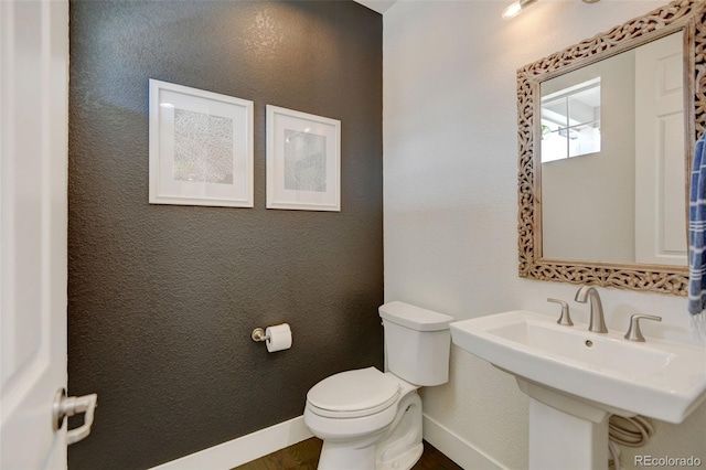 bathroom featuring toilet, baseboards, a sink, and wood finished floors