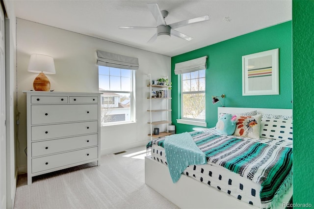 carpeted bedroom featuring ceiling fan, visible vents, and baseboards