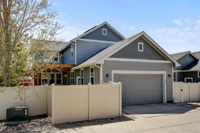view of front facade with fence, driveway, a shingled roof, and a garage
