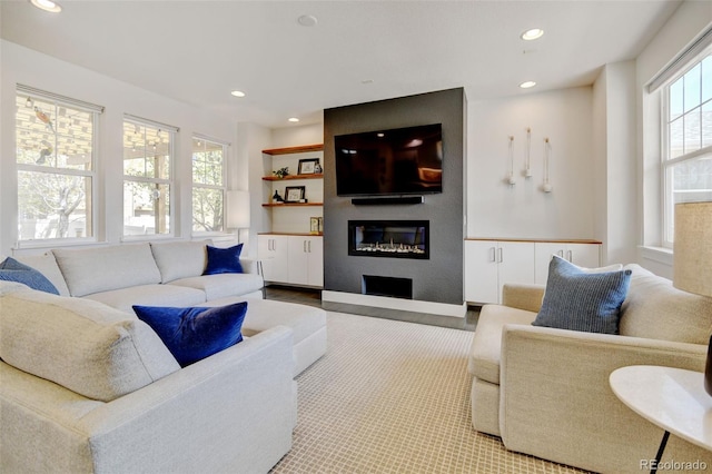 living room with recessed lighting, a glass covered fireplace, and wood finished floors