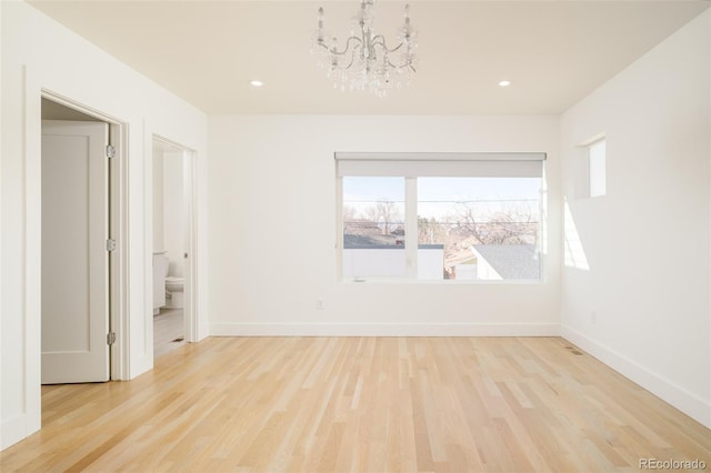 empty room featuring an inviting chandelier and light wood-type flooring