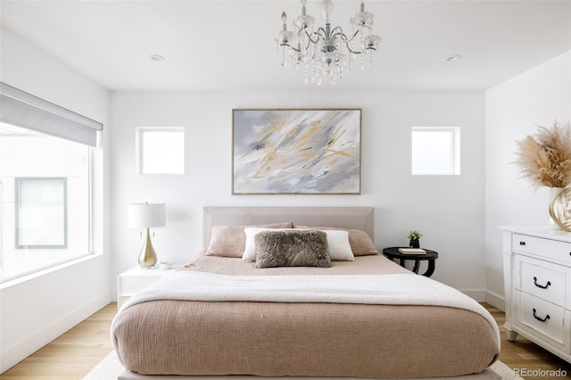 bedroom featuring multiple windows, a notable chandelier, and light hardwood / wood-style floors