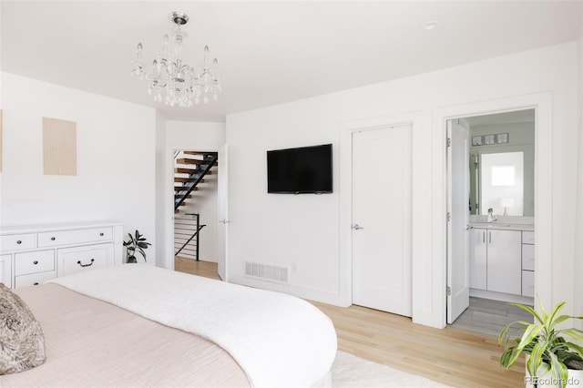 bedroom featuring ensuite bathroom, a chandelier, sink, and light hardwood / wood-style flooring