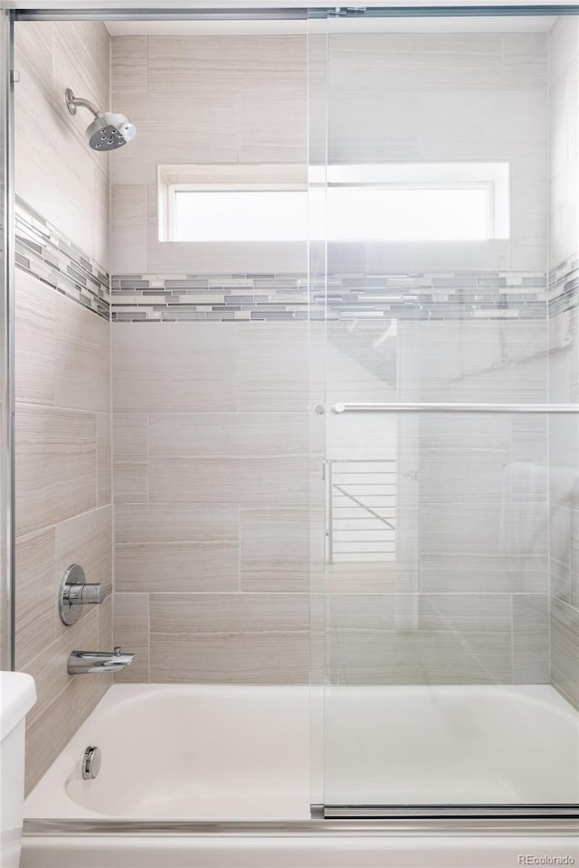 bathroom with bath / shower combo with glass door, toilet, and plenty of natural light