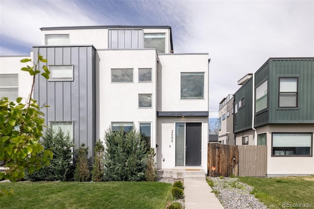 contemporary home featuring a front lawn, fence, and stucco siding