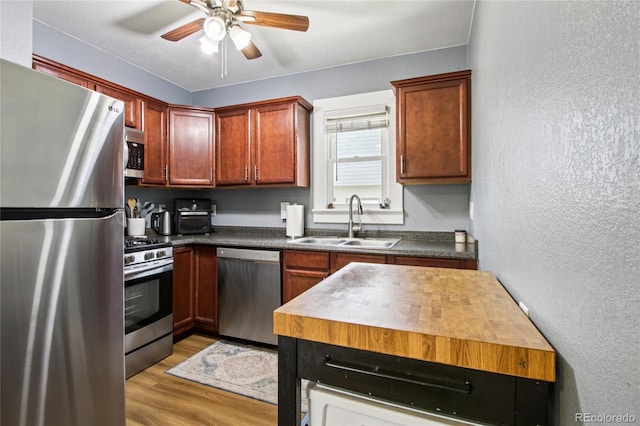 130 N 8th Ave, Brighton, CO 80601 - kitchen with appliances with stainless steel finishes, ceiling fan, light wood-style flooring, dark countertops, and a textured wall